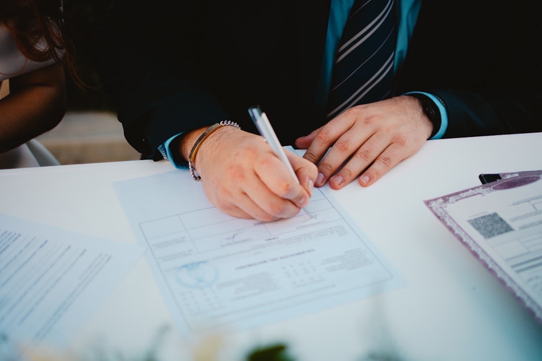 A man in a suit signs a contract on a table.